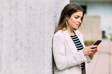 Happy businesswoman using cellphone in the street