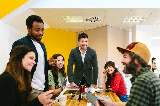 Cheerful interesting colleagues chatting at desk