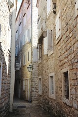 Fototapeta na wymiar Narrow street and a brick wall buildings in old town od Budva, Montenegro