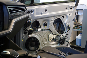 The inner lining has been removed from the door of a modern car. In the doorway you can see the wiring, the music speaker, the power window motor. Car service and electrodiagnostics Concept.