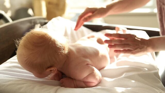 Newborn Baby Lying On The Bed On His Stomach And His Mother Patting Him