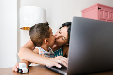 Young woman working at home and taking care of her little son