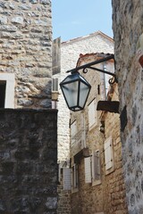 Narrow street with lantern and stone brick walls in an ancient city of Budva, Montenegro on a summer August day