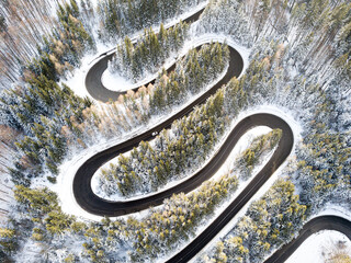 aerial view of a curvy winding road and white snow trees, winter.