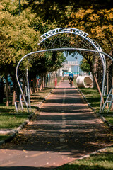 A modern archway over a bike lane street in Burgas. Tree leaves in yellow and orange autumn colours