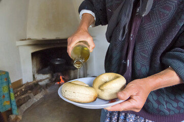 woman sprinkling olive oil on dry bread in Olympos, Karpathos island, Greece