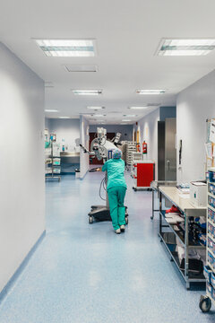 Nurse pulling an hospital machine through the hospital corridor