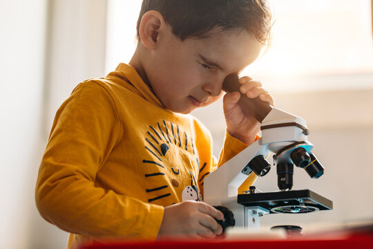 Little kid using a toy microscope