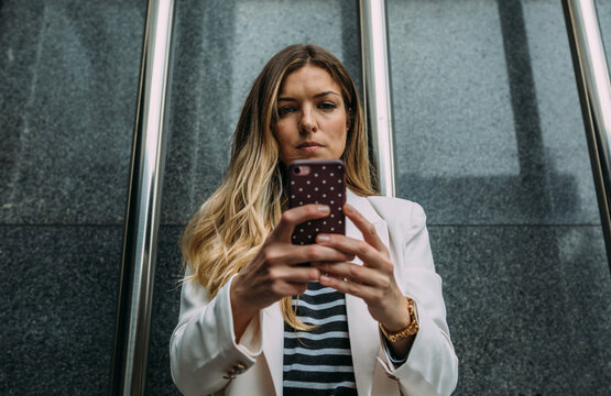 Happy businesswoman using cellphone in the street