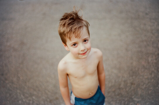 Cute Young Boy Without A Shirt Looking Up At The Camera