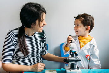 Happy woman playing with her children using a toy microscope