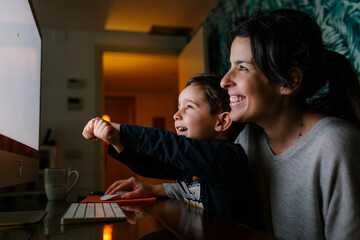 Mother and son having fun while using a computer at night