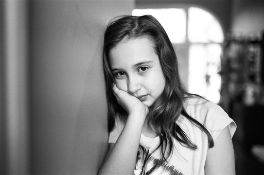 Cute young girl resting her head again a wall