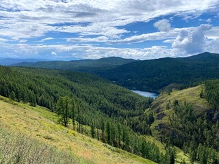 Fototapeta premium Mountain landscape in nature in the open air depicting clouds, conifers and meadows