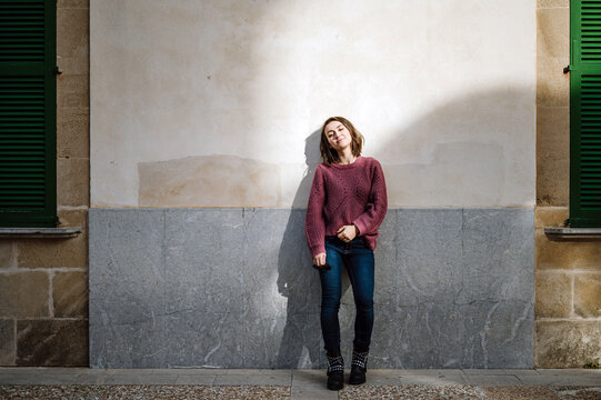 Young woman leaning on wall