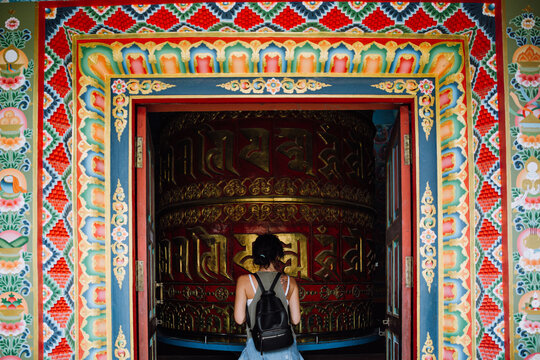 Woman entering a hall with a big prayer wheel
