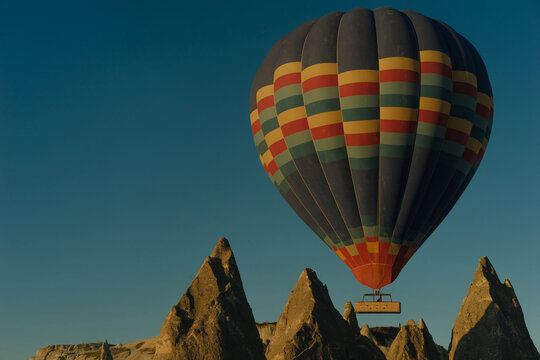 Colored balloon with people over spiky cliffs, Turkey, Cappadocia - Powered by Adobe