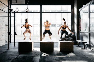 Group of women box jumping during a crossfit training
