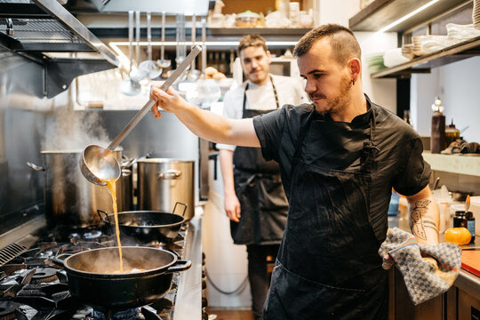 Stylish cook preparing Paella in restaurant