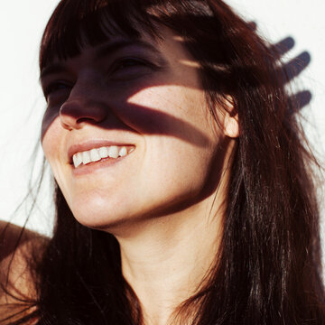 Young woman smiles and hide from the sun