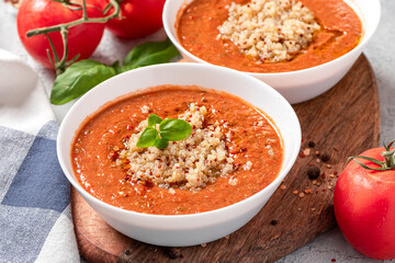 Gazpacho with quinoa. Delicious cold tomato soup with quinoa, peppers, cucumbers, olive oil and spices in a white bowl close-up. Vegan and vegetarian food, Mediterranean cuisine.