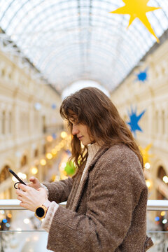 girl looks at the phone screen in the gallery of the state department store in Moscow