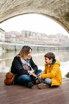 Mother and son talking sat next to the city river