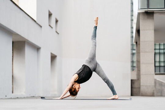 Young woman doing eka pada adho mukha svanasana yoga pose