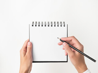 hands holding a square spiral notebook with blank white pages on white isolated background. woman is going to write notes in notebook with black pencil. mockup, space for text. education concept