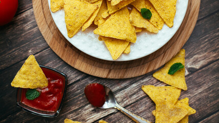 tortilla chips in a white bowl with tomato dip on a wooden table