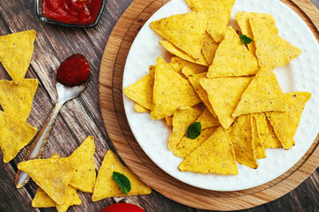tortilla chips in a white bowl with tomato dip on a wooden table