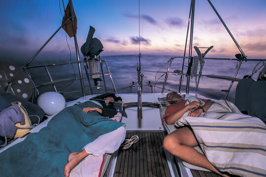 a couple of sailors sleep on deck during an ocean crossing