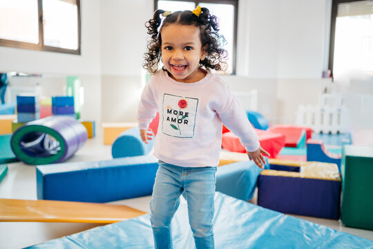 Happy ethnic girl playing in kindergarten