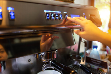 A woman's hand is using a freshly brewed coffee machine to serve the customers in the coffee shop.