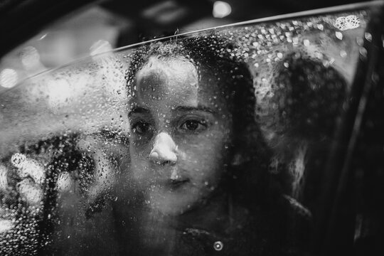Kid in the rain inside a car