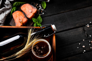  Beer with salted red fish on black wooden background