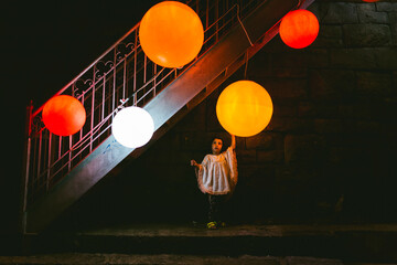 Scene of a kid under the stairs touching a big orange lamp