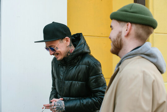 Two stylish friends smile and chat on the street