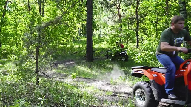 Long shot. The guys, the men on the ATV, make a sharp turn. The ATVs in the woods turn sharply. Extreme turn on a quad bike
