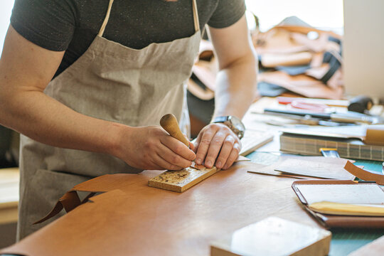 the master makes holes with an awl in the blank for a leather product