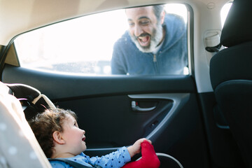Baby inside a car smiling at dad