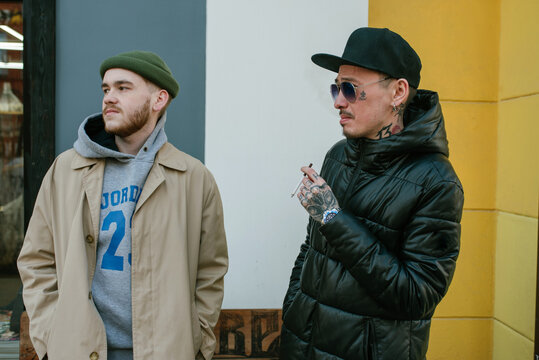Two stylish friends smile and chat on the street