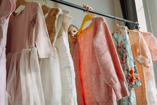 Girl choosing dresses on a clothing rack - Powered by Adobe