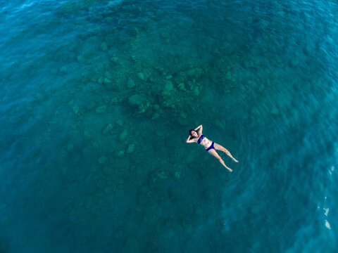 aerial image of a woman floating in dark turquoise water