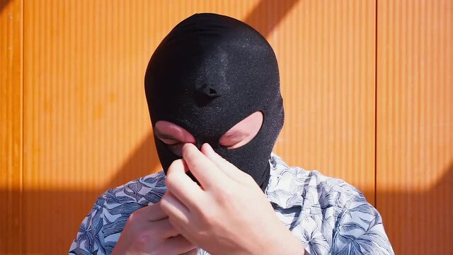 The man puts on a mask, a black balaclava over his face. Hide the face from recognising part of the anonymity. Street bully.