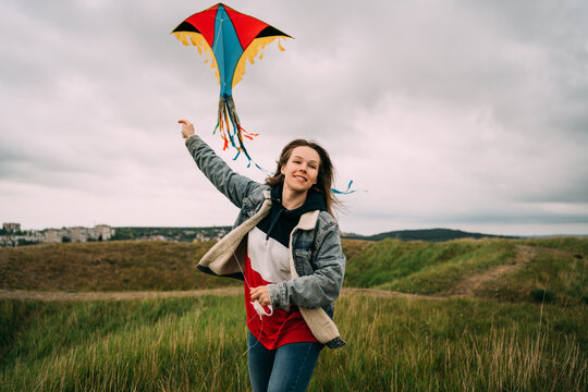 Smilimg young woman launches colorful kite