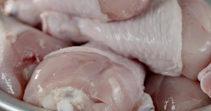 Fresh chicken raw drumstick pieces slowly rotate. 
