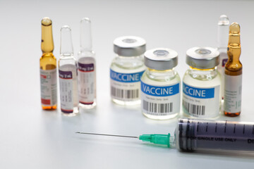Syringe needle with vaccine bottles and injection vials in closeup view