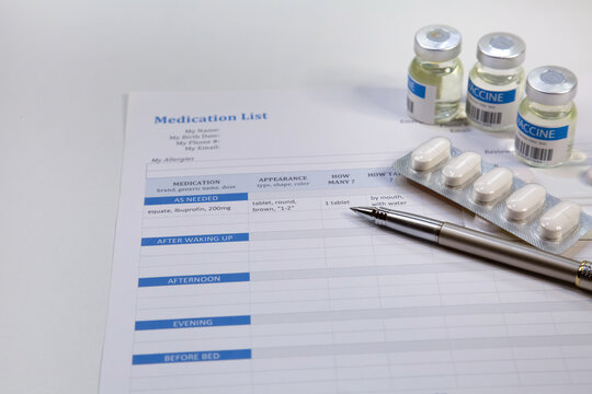 Patient medication list with pen along with vaccine bottles and tablets at a medical clinic at Kolkata
