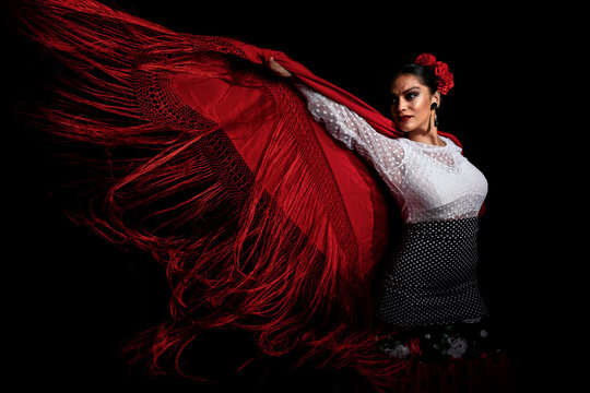 Seductive young Hispanic female in traditional red costume performing sensual Flamenco dance and looking away